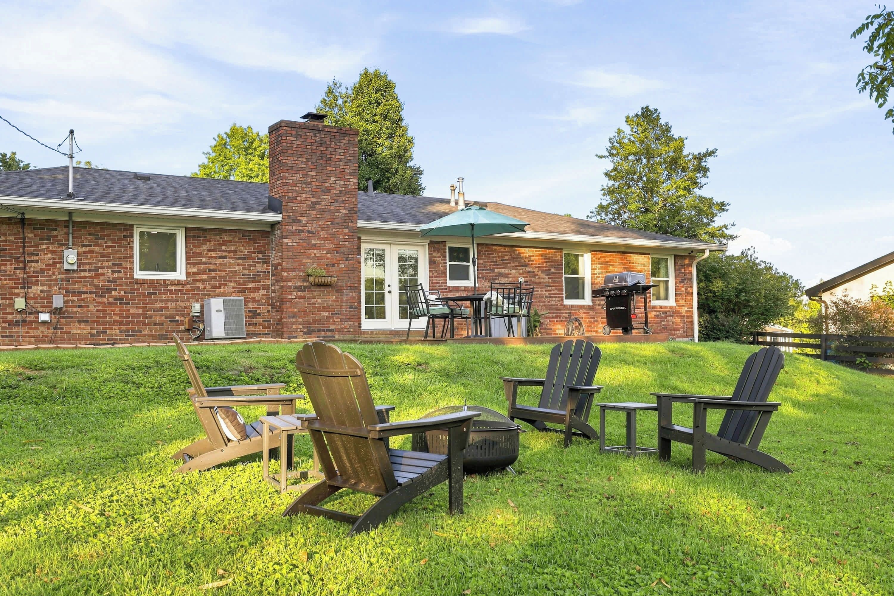 Una casa de ladrillo con un patio, mobiliario exterior y una parrilla.