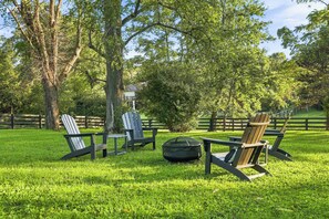 A grassy outdoor area with Adirondack chairs and a fire pit.