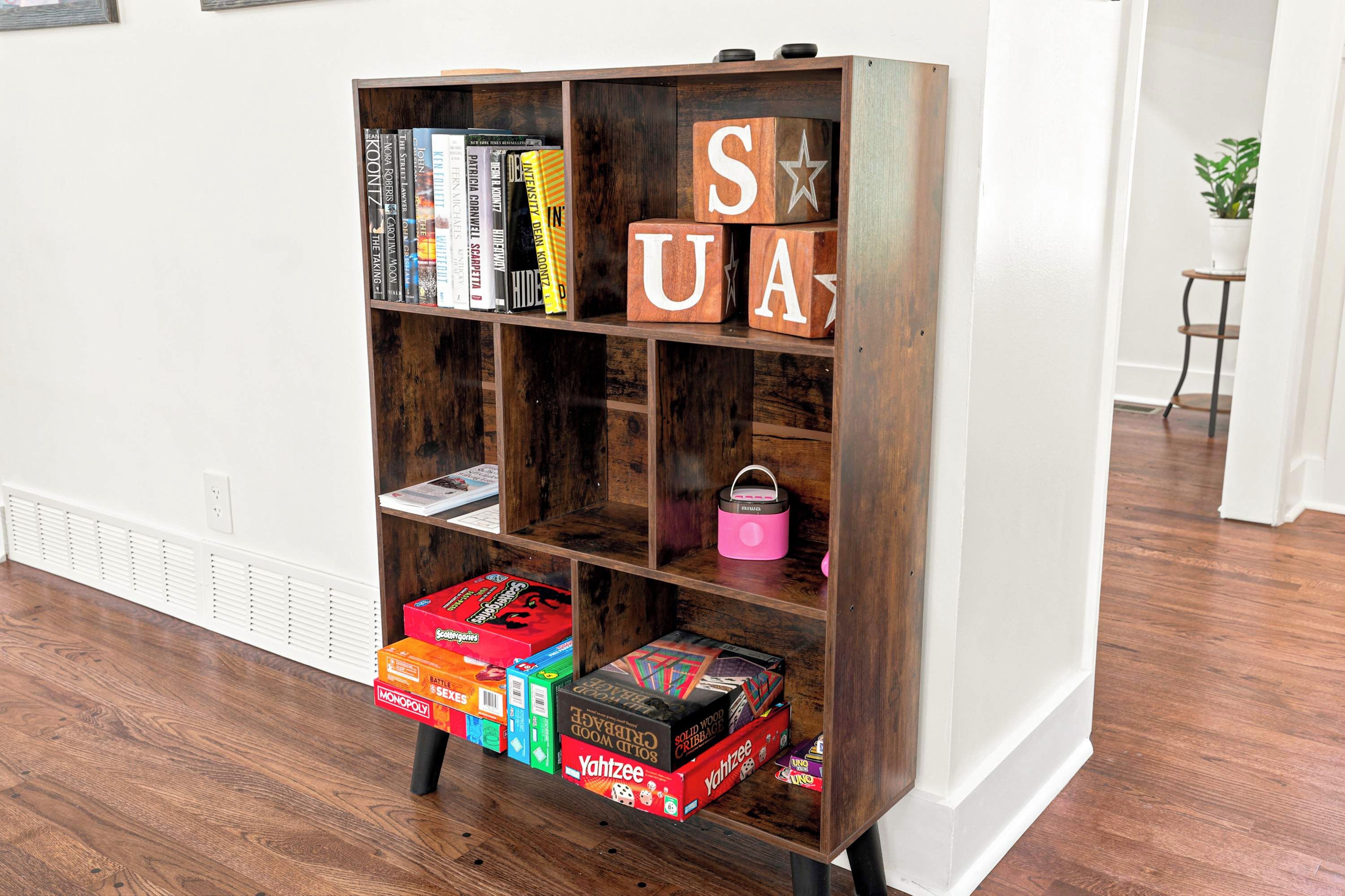 Une bibliothèque en bois avec des livres et des boîtes de jeux.