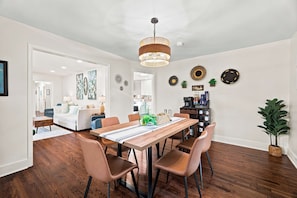 A dining area with a wooden table, chairs, and a hanging light fixture.