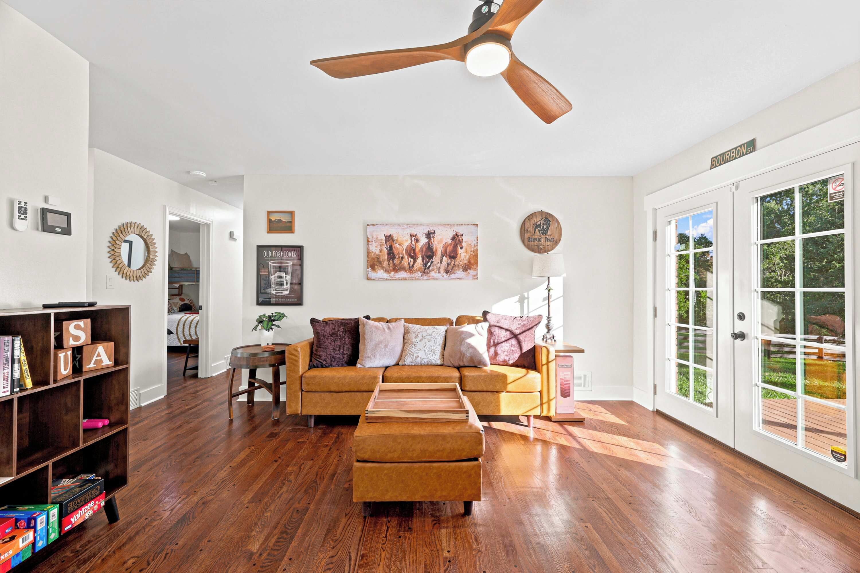 A spacious living room with hardwood flooring, a brown sofa, a coffee table, and a ceiling fan.
