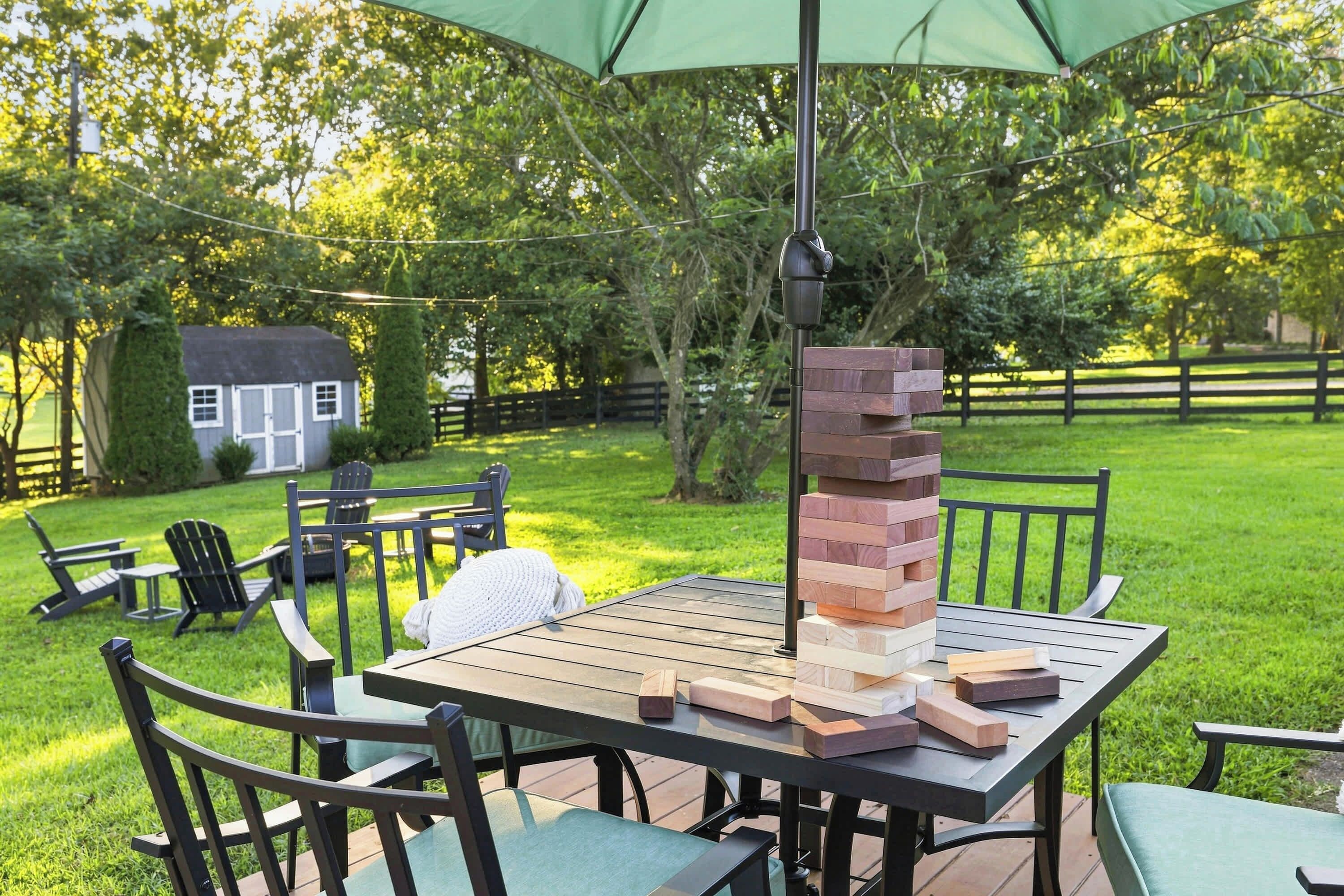 An outdoor patio with a table, chairs, and a stack of wooden blocks.