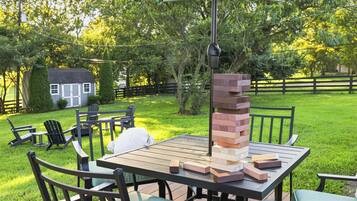 An outdoor patio with a table, chairs, and a stack of wooden blocks.