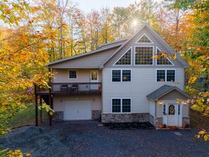 A two-story house with a garage, a balcony, and a small porch area. - Thanksgiving Open! 6-bedroom, 2 Kitchens, Hot Tub, Game Rm, Piano, Fire Pit,  (Pocono Lake)