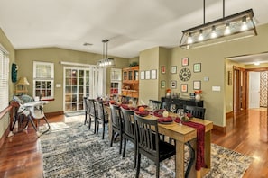 A dining area with a wooden table set for six, surrounded by chairs, with a chandelier above. - Thanksgiving Open! 6-bedroom, 2 Kitchens, Hot Tub, Game Rm, Piano, Fire Pit,  (Pocono Lake)