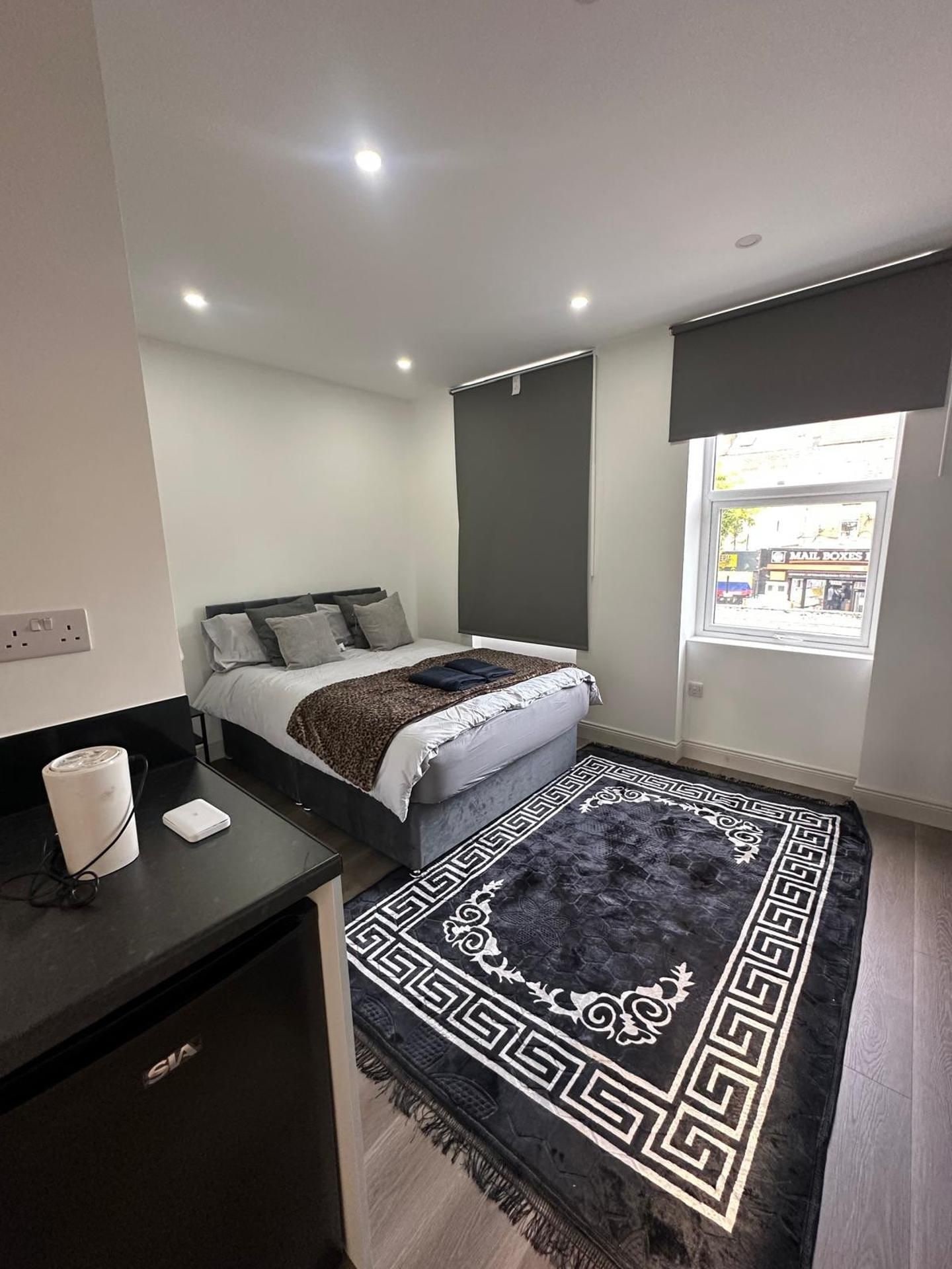 Un dormitorio moderno con cama, mesita de noche y vista a la calle.