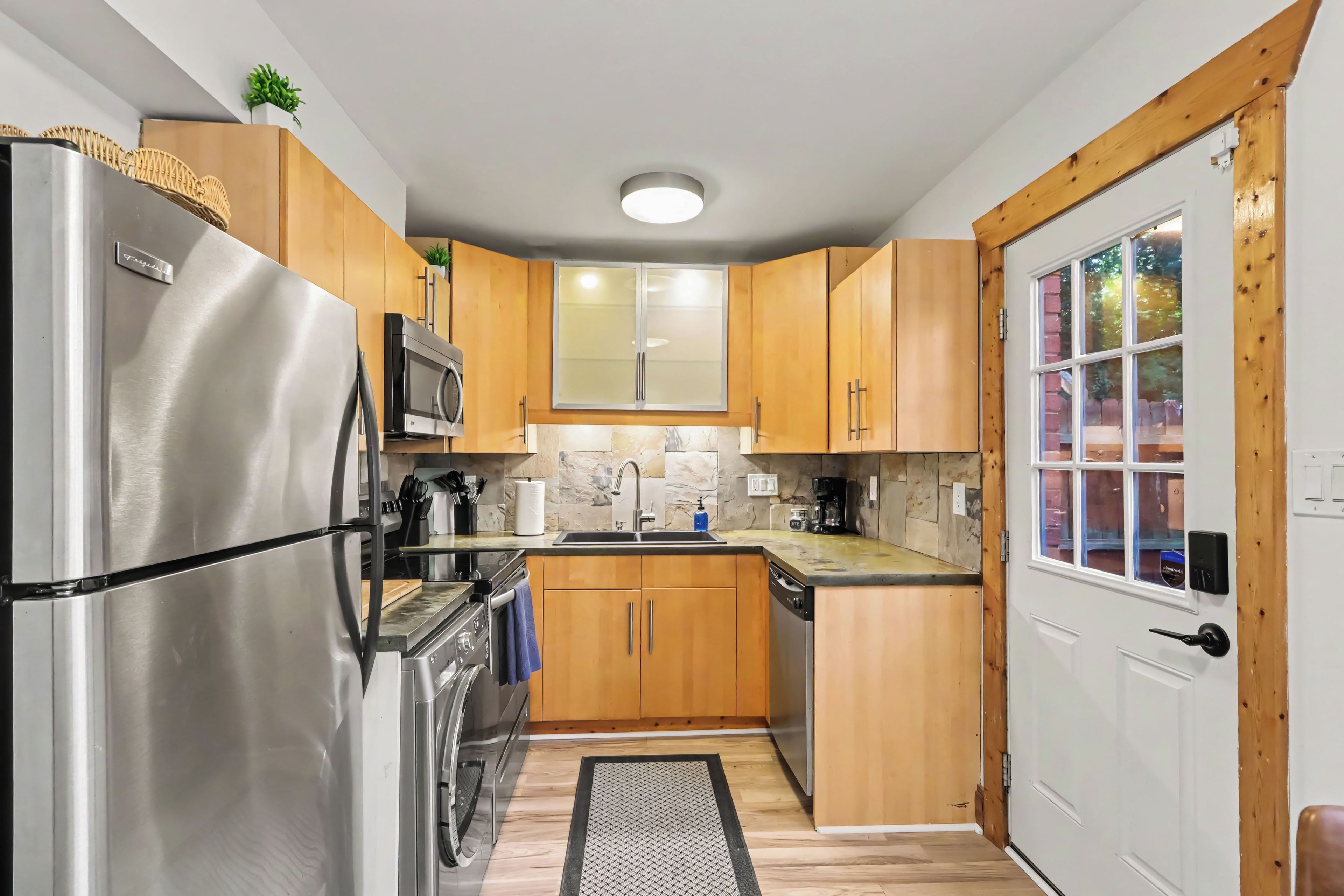A compact kitchen with wooden cabinets, stainless steel appliances, and a window.