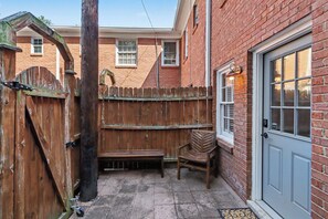 A brick building with a wooden fence, a bench, and a chair outside. - Cozy King Condo Walk to Bojangles & Ovens (Charlotte)