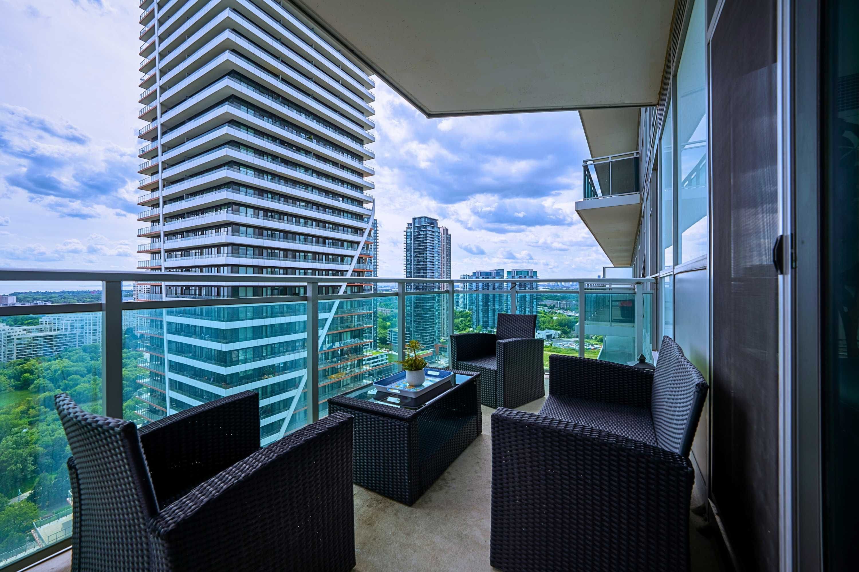 A balcony with wicker furniture and a city view.