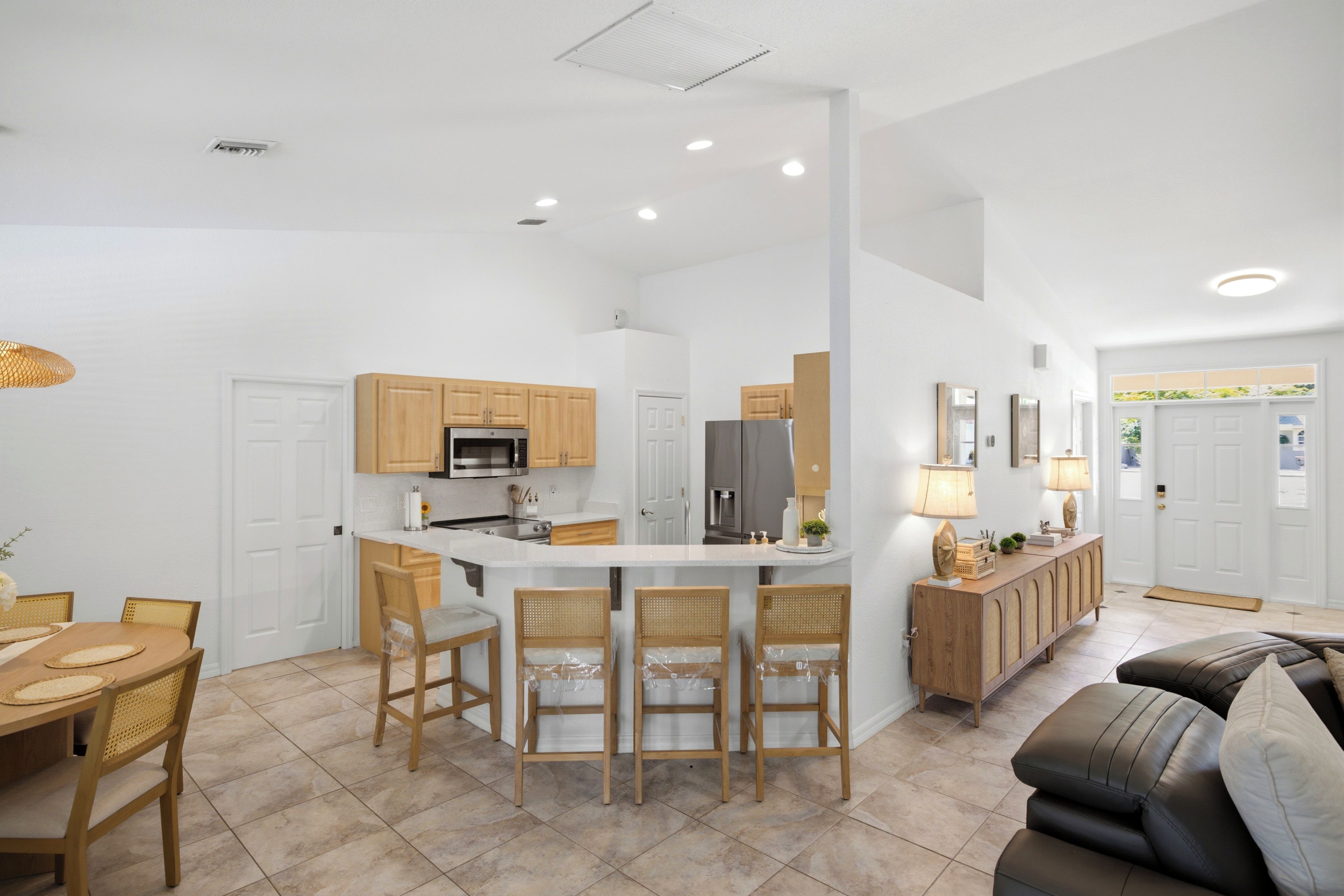 A modern kitchen with a central island, wooden cabinets, and a dining area with a table and chairs.