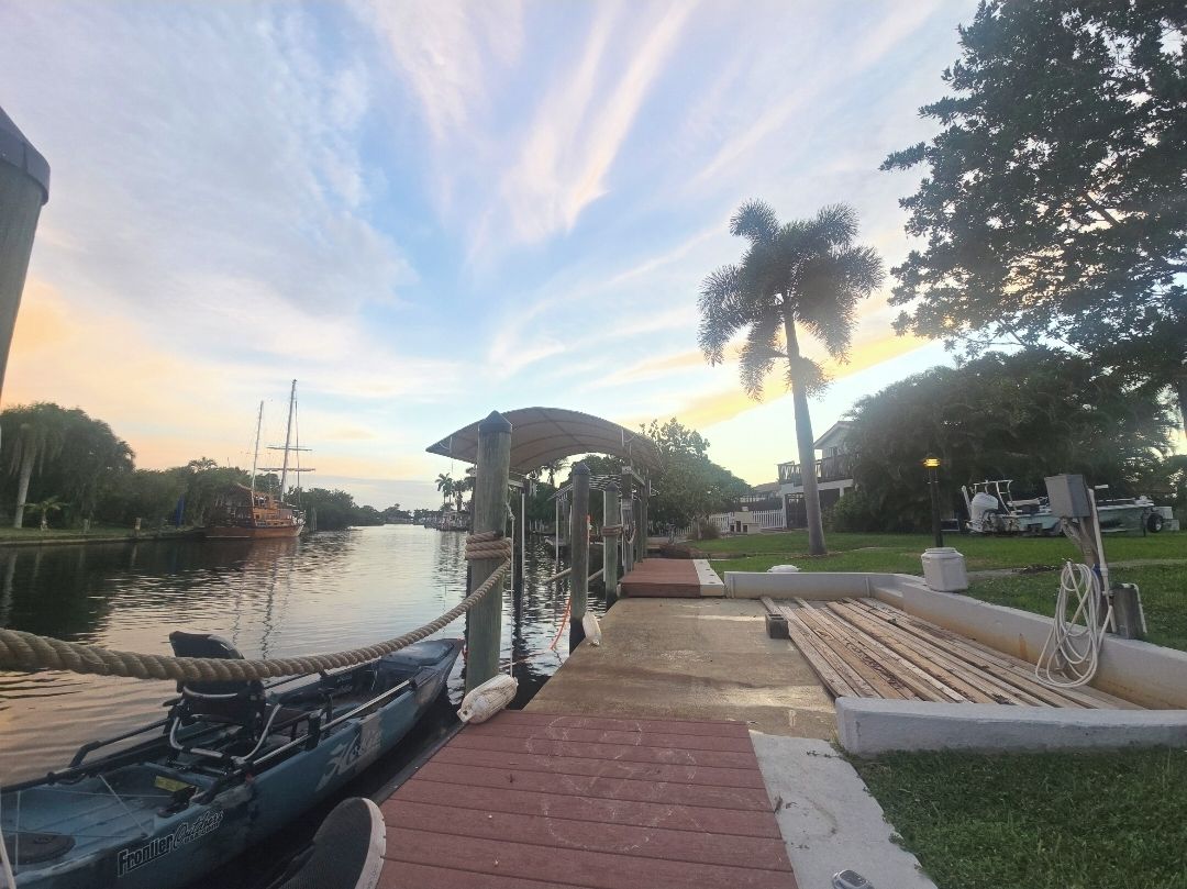 Un muelle con barcos, un canal navegable y un atardecer.