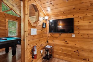 A wooden interior with a pool table, a television, and a fire extinguisher. - Private Theater & Hot tub with Arcade and 3 King Beds (Sevierville)