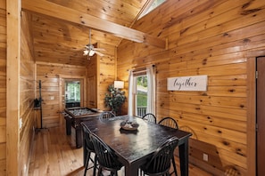 A wooden interior with a dining table, chairs, a foosball table, and a ceiling fan. - Private Theater & Hot tub with Arcade and 3 King Beds (Sevierville)