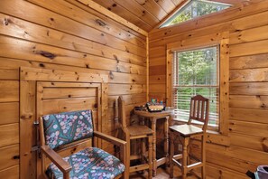 A cozy wooden cabin interior with a dining table, two chairs, and a window with blinds. - Private Theater & Hot tub with Arcade and 3 King Beds (Sevierville)