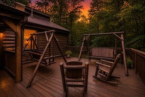 A wooden deck with a swing set, a bench, and a small table. - Private Theater & Hot tub with Arcade and 3 King Beds (Sevierville)