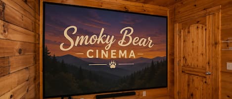 Una sala de cine con una pantalla grande mostrando 'Smoky Bear Cinema' y vistas a la montaña.
