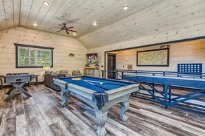 Une pièce équipée d’une table de billard, d’un baby-foot et d’un ventilateur de plafond.