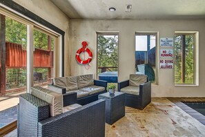 Une véranda meublée de mobilier en osier, avec une bouée et un panneau indiquant qu’il faut se présenter avant d’entrer.