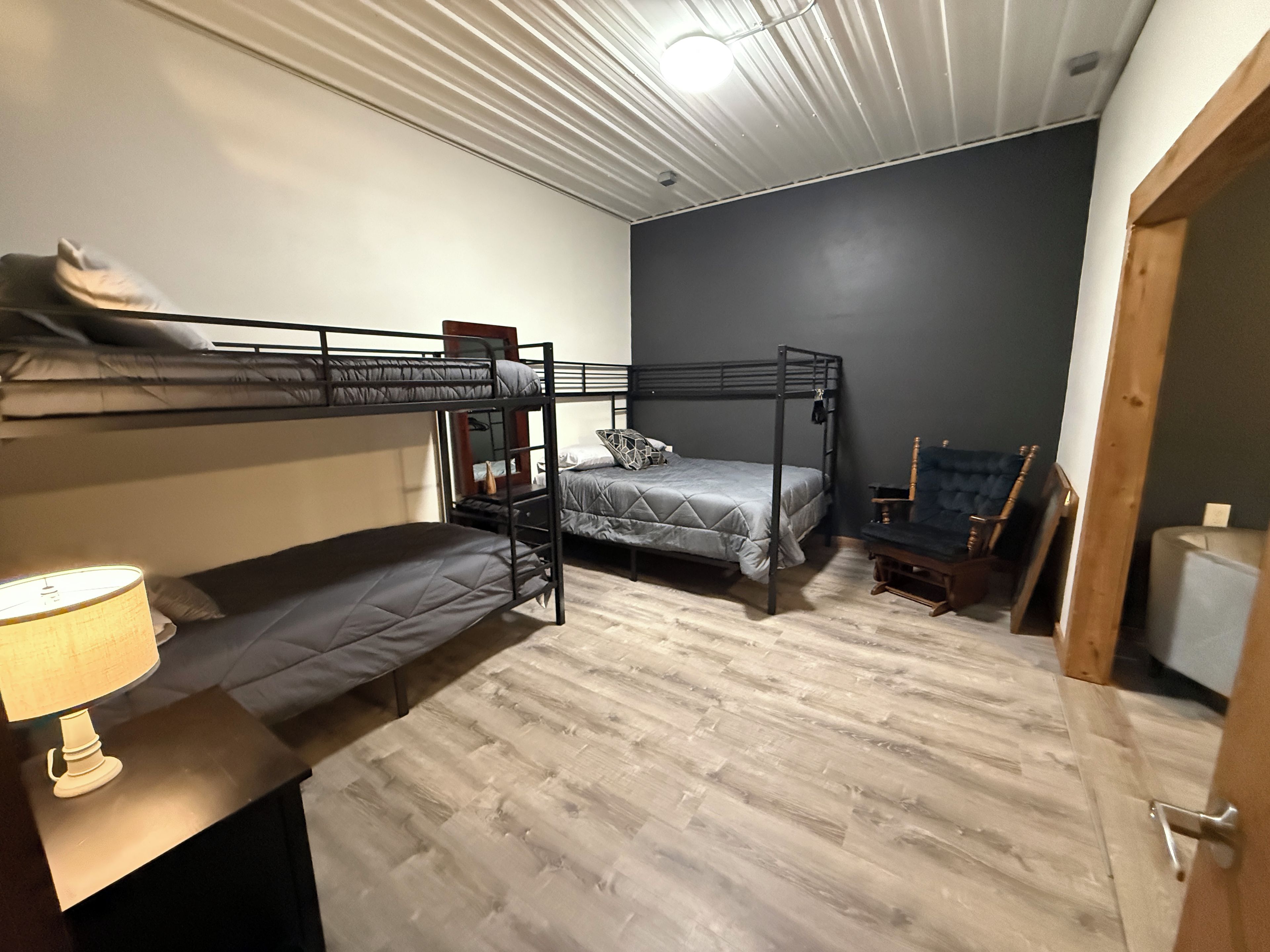 A room with bunk beds, a lamp, a chair, and a guitar.