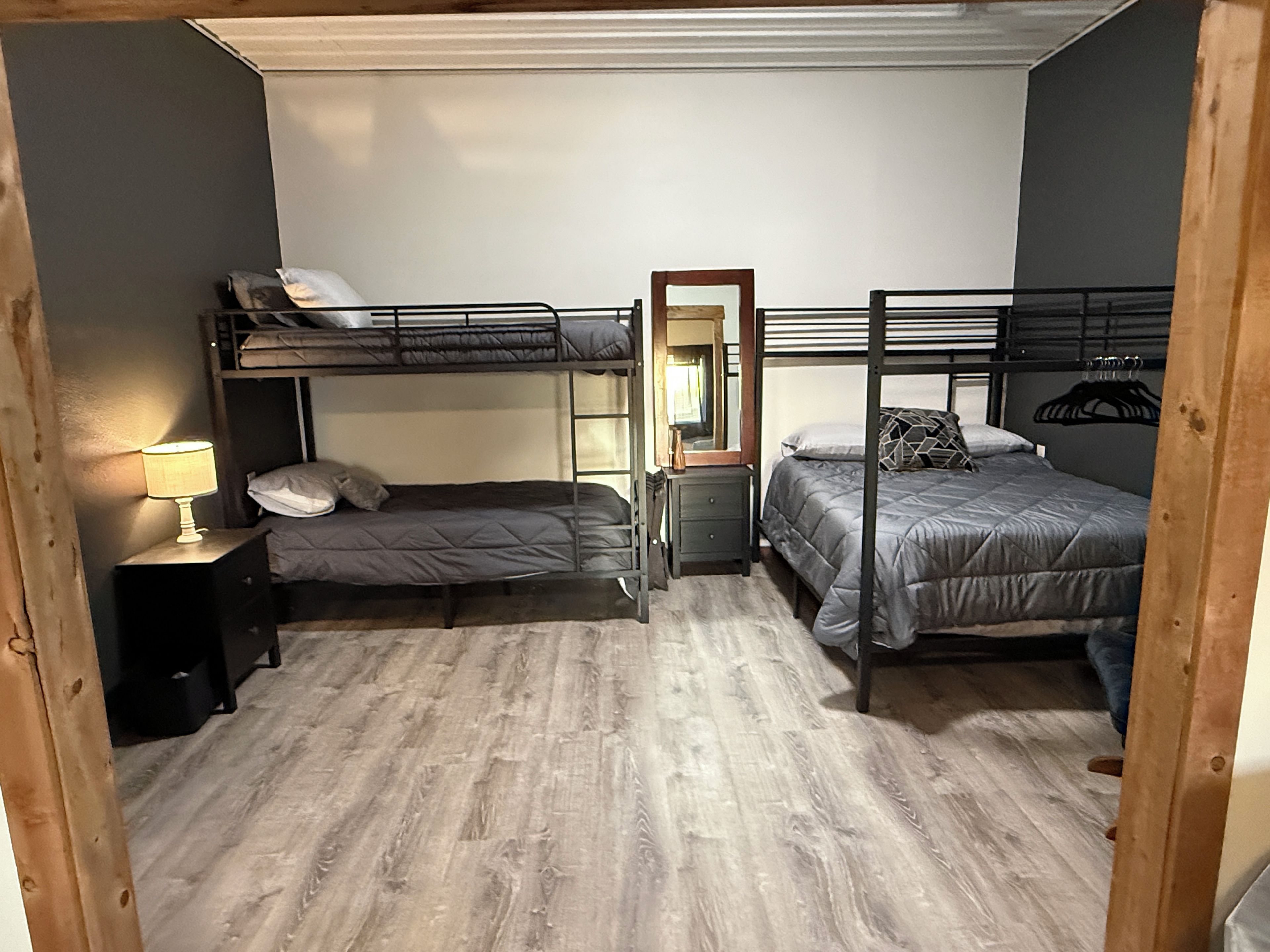 A compact room with bunk beds, a bedside table with a lamp, and a mirror.