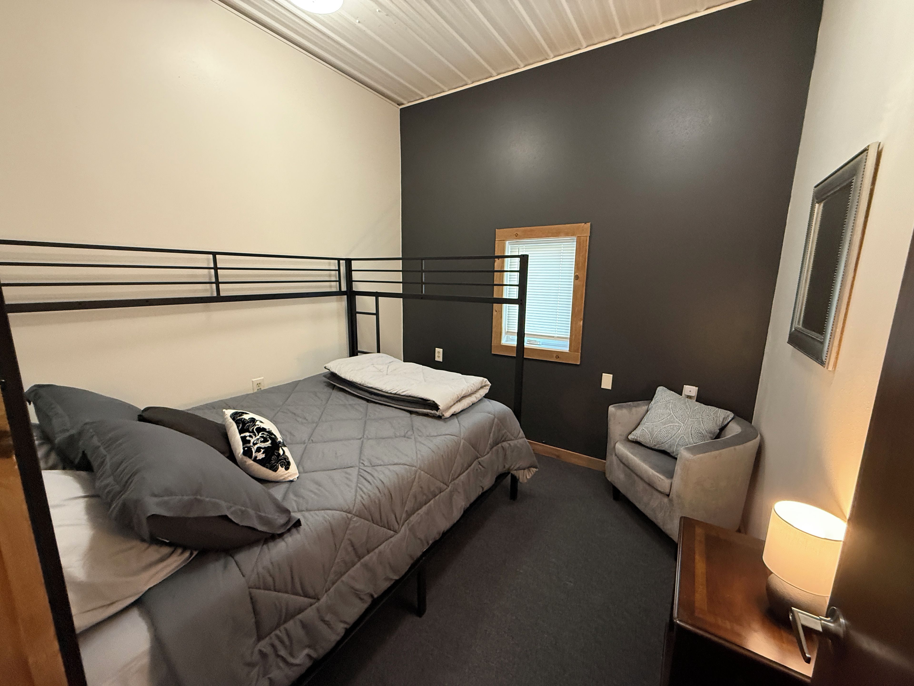 A bedroom with a bed, a bedside table, a chair, and a window.