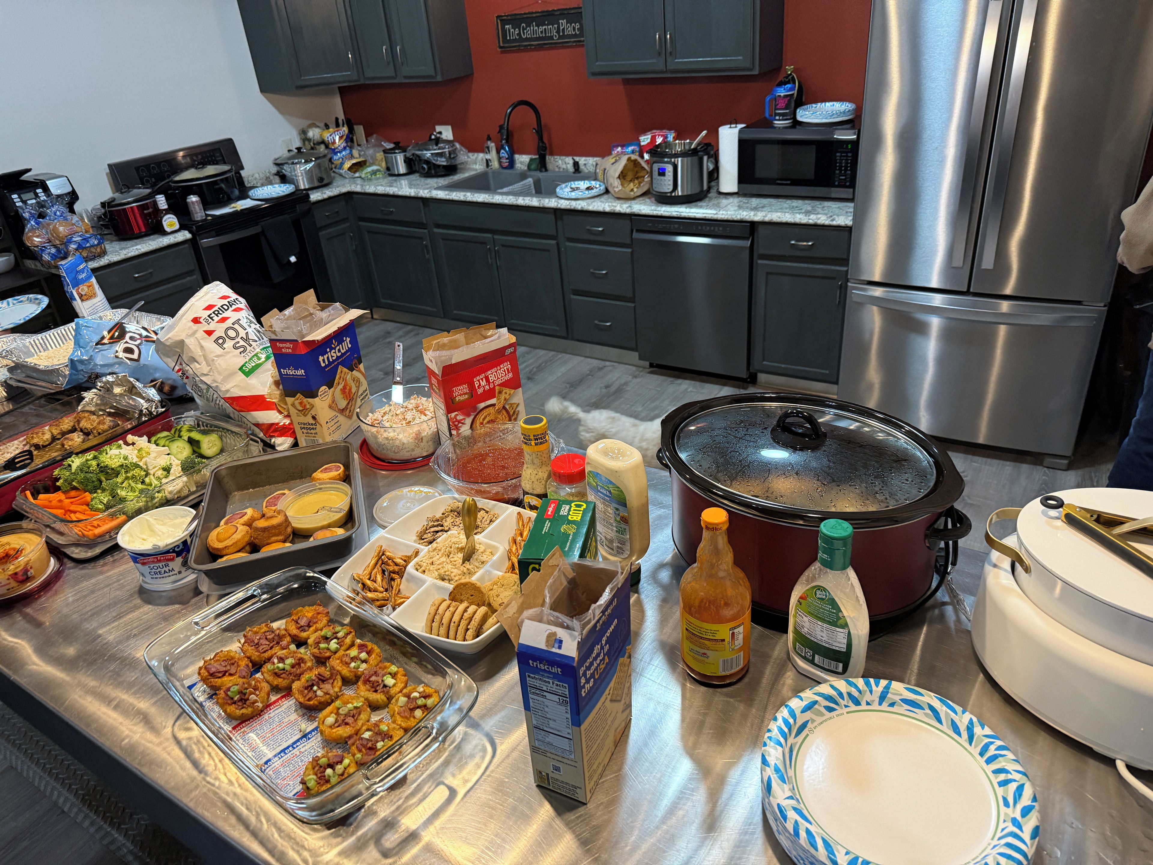 A kitchen with a stainless steel refrigerator, a microwave, and a large pot on the stove.