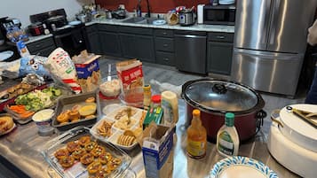 A kitchen with a stainless steel refrigerator, a microwave, and a large pot on the stove.