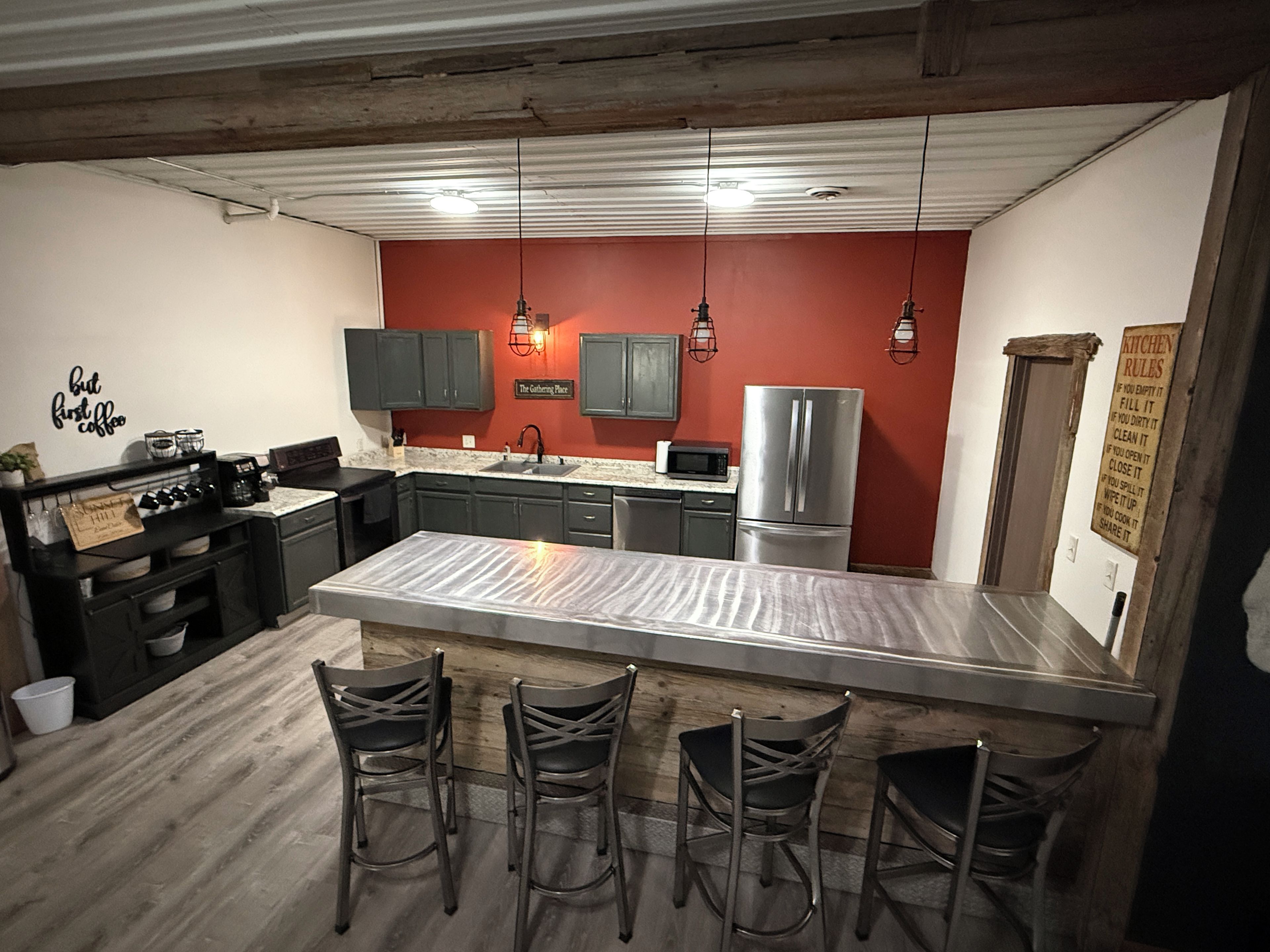 A kitchen with a central island, dark cabinets, and a red accent wall.