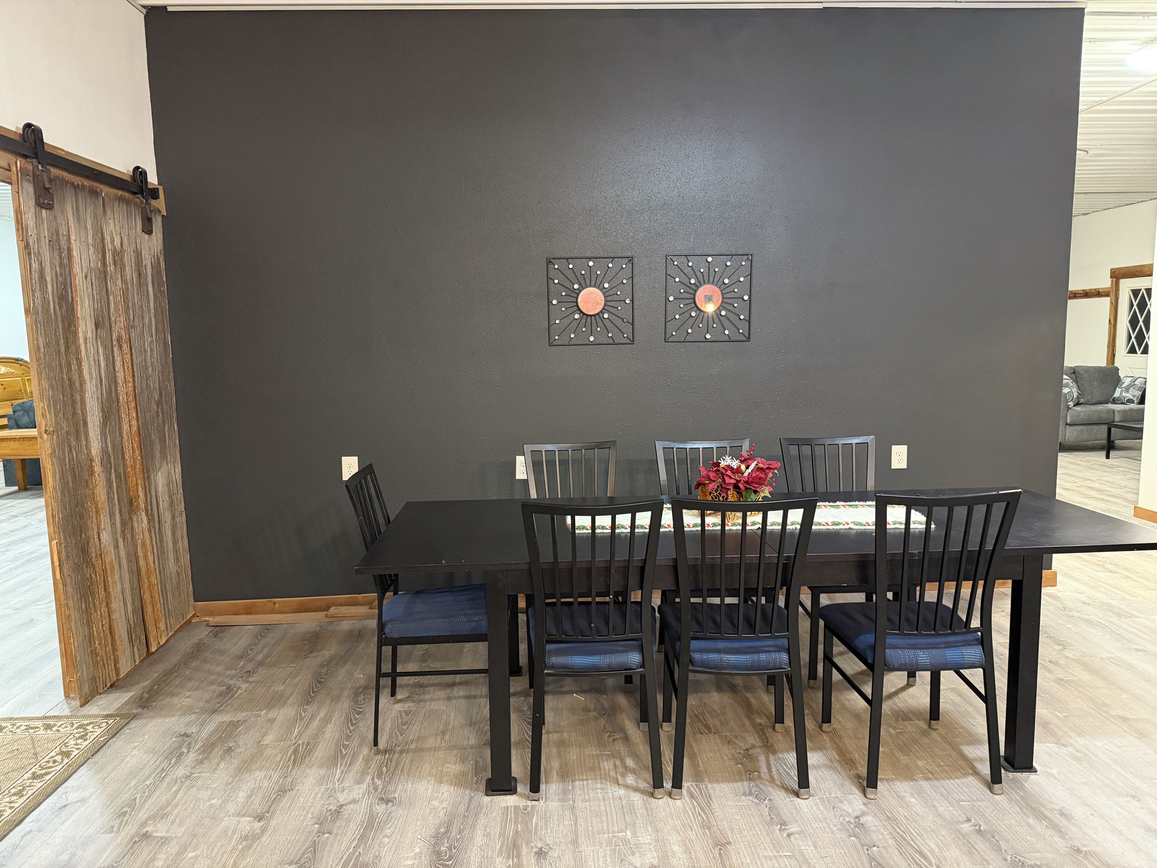 A dining area with a dark wall, a wooden-framed table, and six chairs.