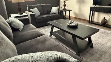 A living room with a sofa, coffee table, and a television.