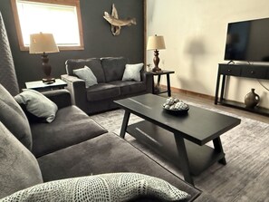 A living room with a sofa, coffee table, and a television.