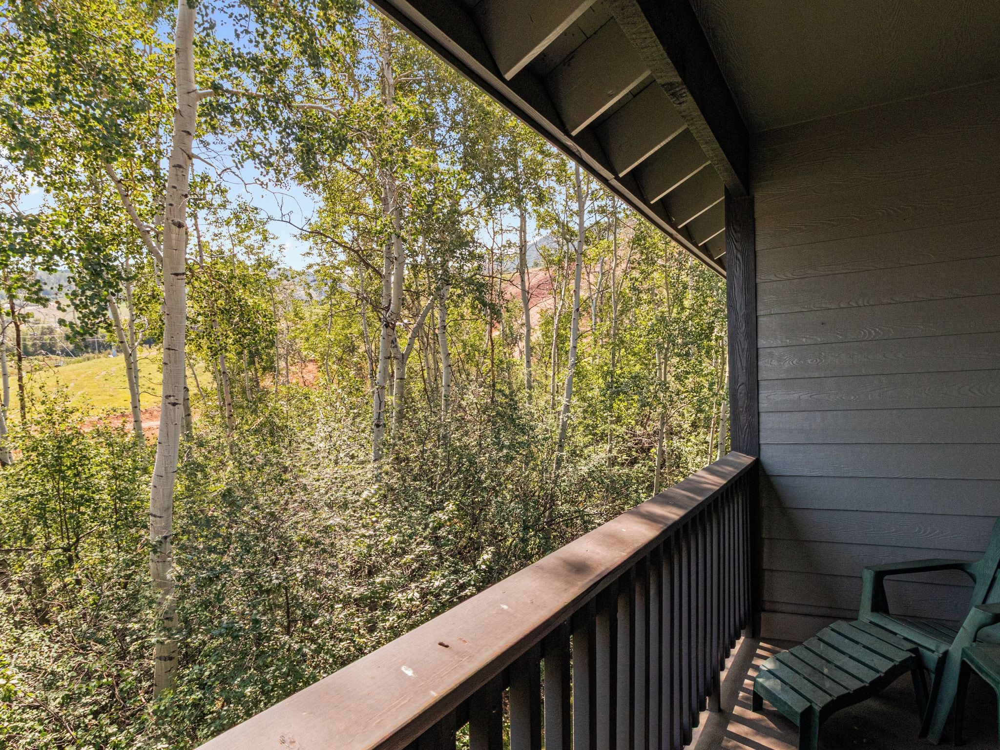 Un balcon en bois donnant sur une zone boisée.