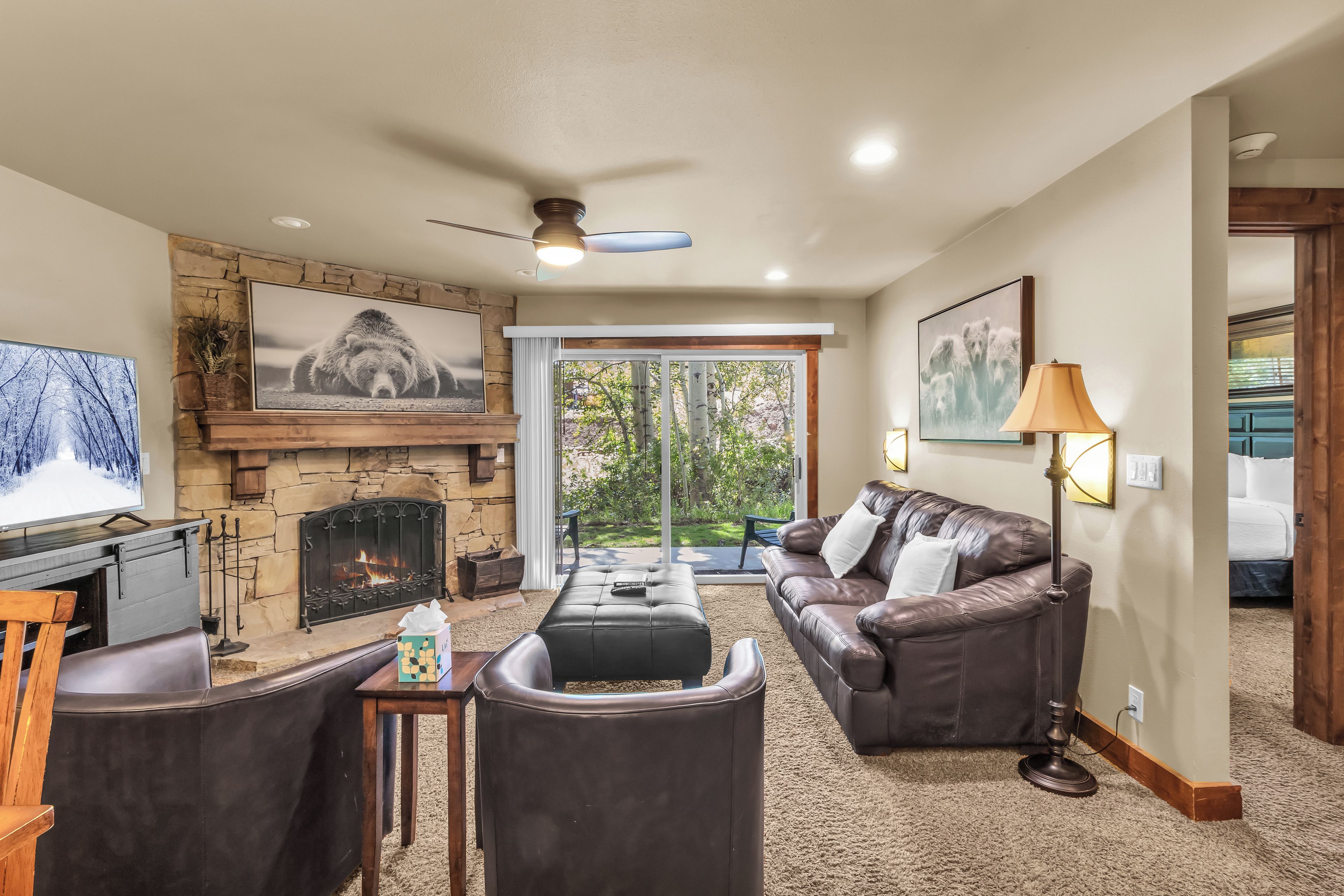 A living room with a fireplace, leather furniture, and a television.