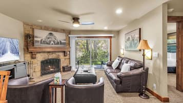 A living room with a fireplace, leather furniture, and a television.