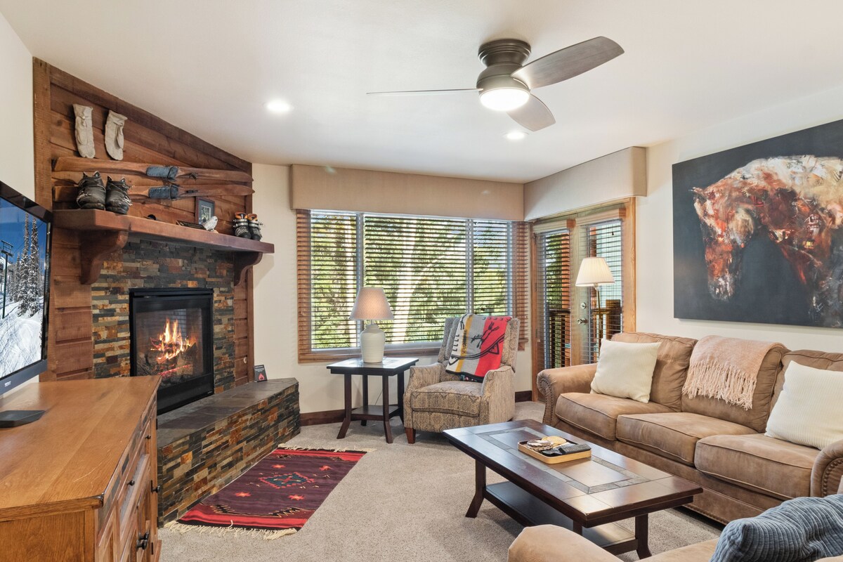 Una sala de estar con chimenea, un sofá, una mesa de centro y un televisor.