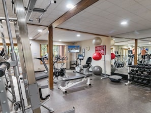 Un gimnasio con diversos equipos de ejercicio, incluyendo cintas de correr, bicicletas estáticas y máquinas de pesas.
