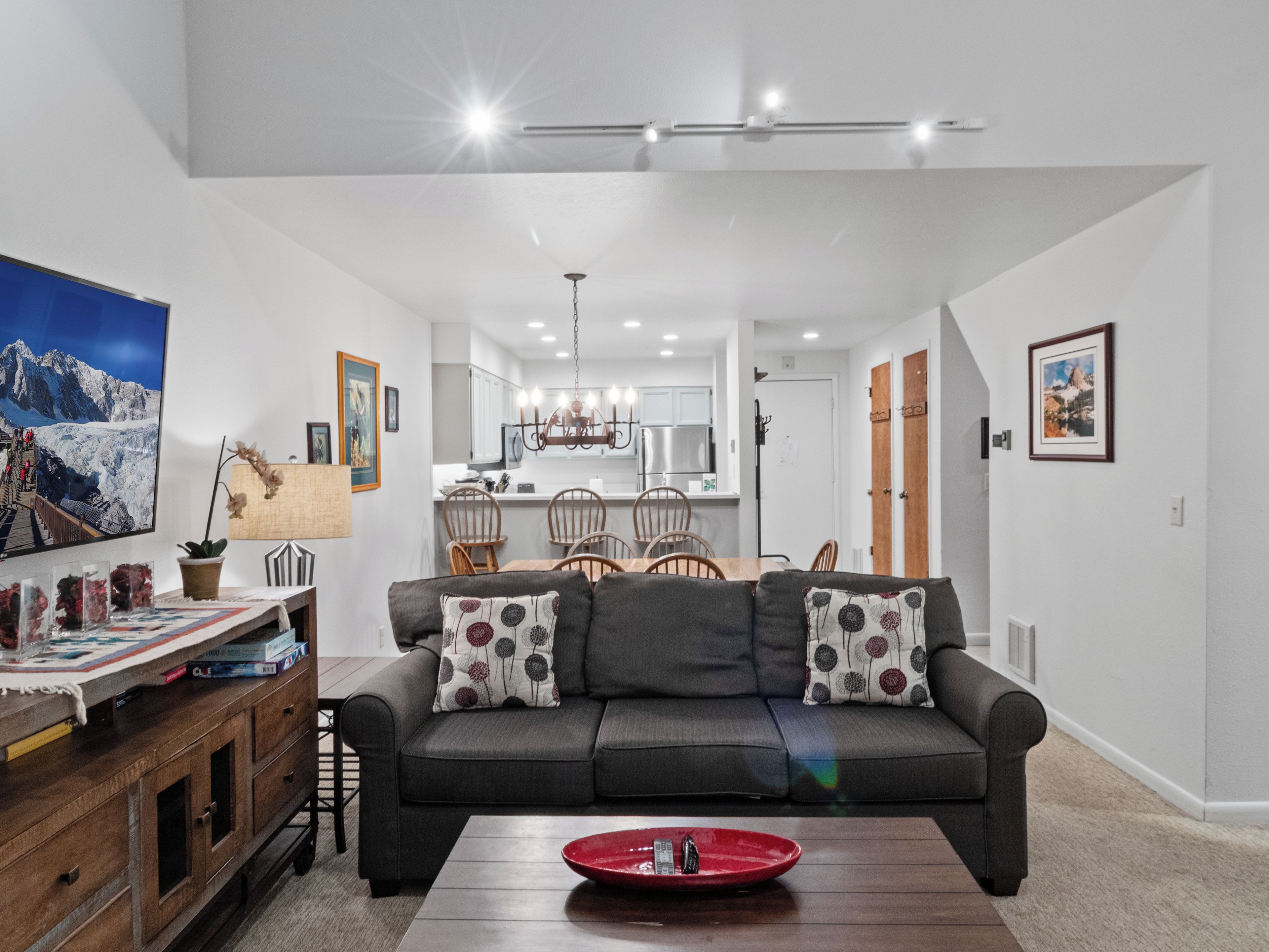Un salon moderne avec un canapé, un coin repas avec des chaises et une cuisine en arrière-plan.