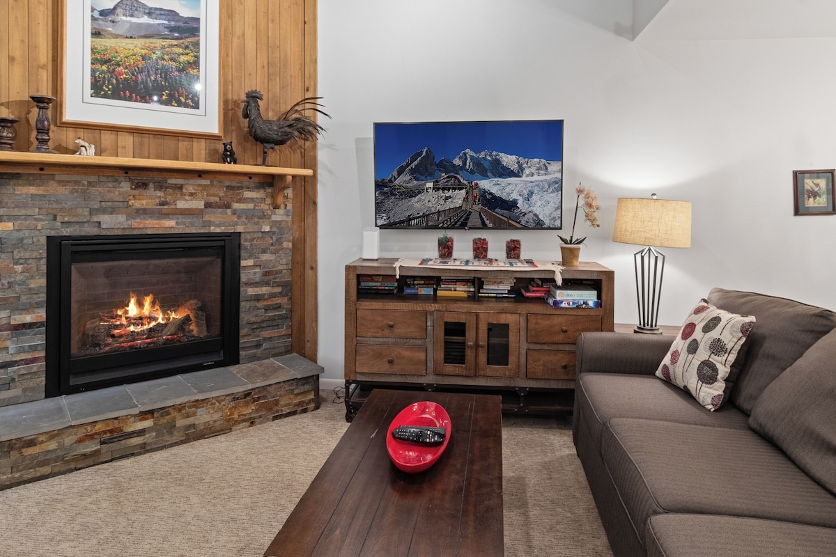 Una sala de estar con chimenea, un cuadro colgado, una estantería y un sofá.