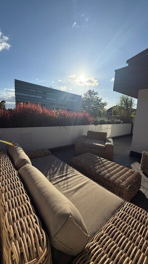 Un espace extérieur moderne, aménagé pour se détendre, avec vue sur un bâtiment et un jardin paysager.