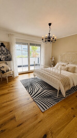 Ein Schlafzimmer mit einem Bett, einer Kandelaber, einem Fenster und einer Tür.