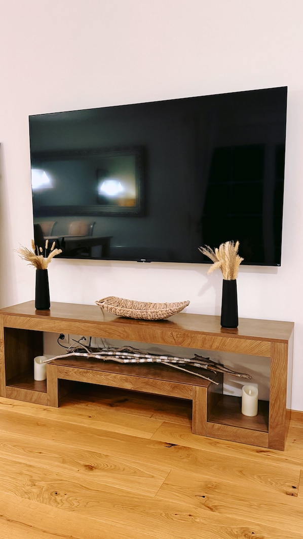A wooden console table with a flat-screen TV mounted above it.