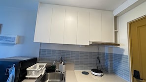 Une cuisine de taille réduite avec des meubles blancs, un évier et un four à micro-ondes.