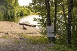 Une zone au bord du lac, avec un quai, des chaises et un panneau d’avertissement.