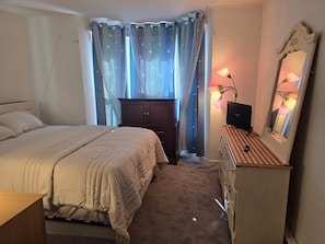 Een slaapkamer met een bed, een kaptafel, een spiegel en een lamp.