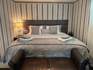 Ein Hotelzimmer mit einem großen Bett, einem Nachttisch, einer Lampe und einem Sessel.