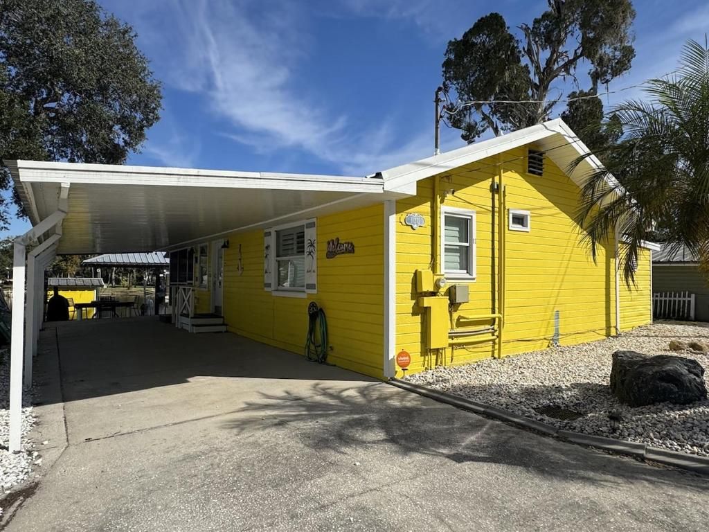 Un bâtiment jaune doté d’un espace extérieur abrité, d’une enseigne indiquant le mot « Plus » et d’une petite fenêtre.