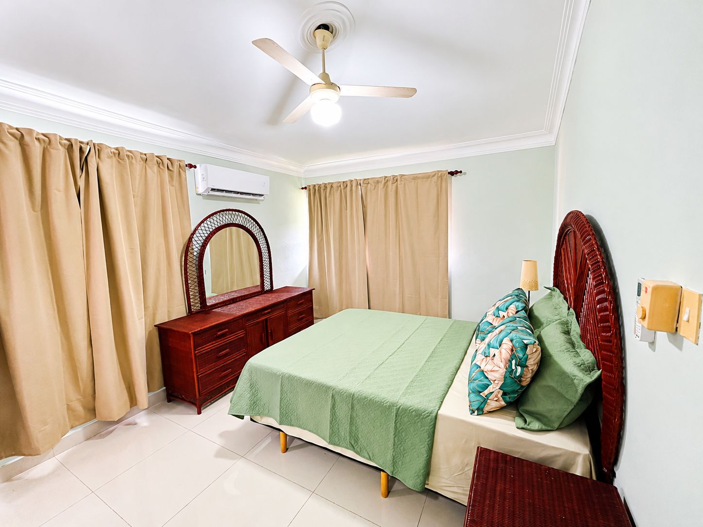 A bedroom with a bed, a dresser, a mirror, and a ceiling fan.