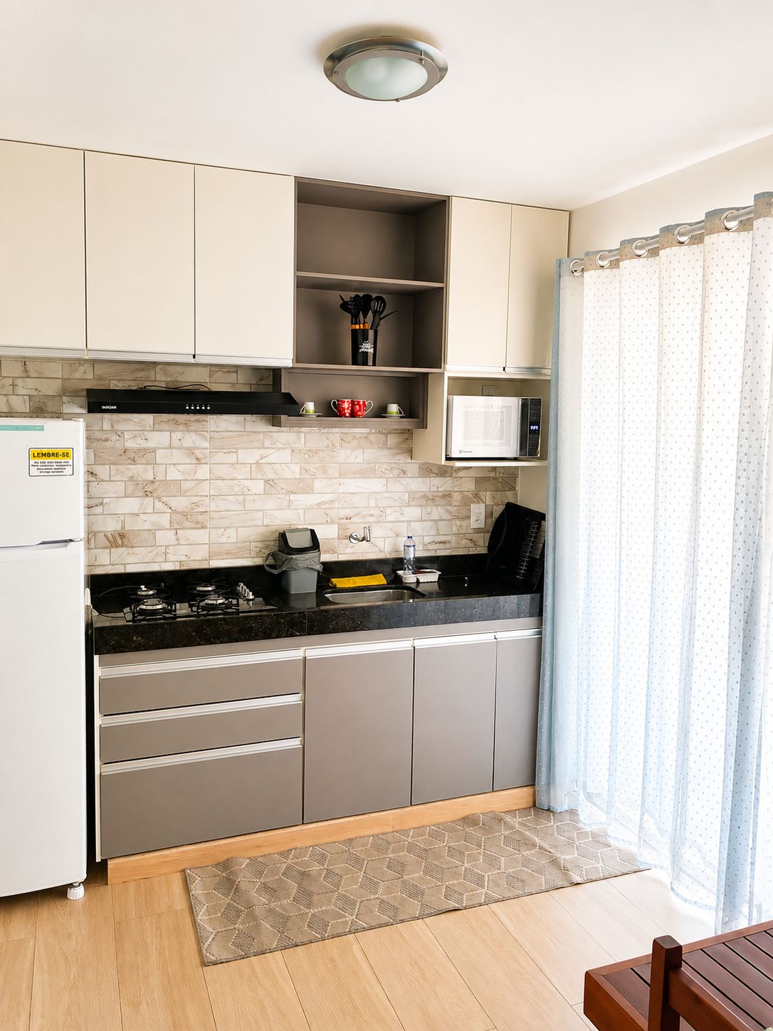 Une cuisine moderne équipée d’un four à micro-ondes encastré, d’une cuisinière à gaz et d’un réfrigérateur.