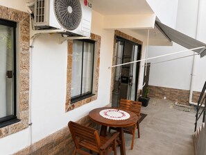 An outdoor patio with a round wooden table and chairs, a ceiling fan, and a sliding glass door leading to a kitchen. - Fully furnished loft with pool, garage, and laundry room. (Araruama)