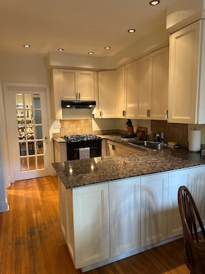 A kitchen with white cabinets, a granite countertop, a stove, and a sink.